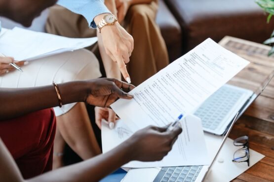 A person holding a document with other people pointing at it.